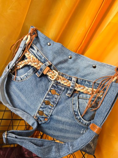 Jeansshorts mit einem geflochtenen Gürtel und Fransen, vor einem orangefarbenen Hintergrund.