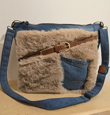 Tasche aus Jeansstoff mit einem flauschigen, beigen Einsatz und braunem Gürtel.