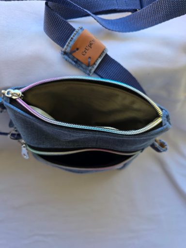 Rucksack mit buntem Reißverschluss, geöffnet, zeigt zwei Innenfächer.