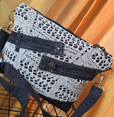 Tasche aus gehäkeltem Material in Schwarz und Weiß mit verstellbarem Schulterriemen.