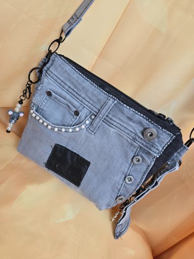 Graue Umhängetasche mit Jeans-Design und dekorativen Elementen.