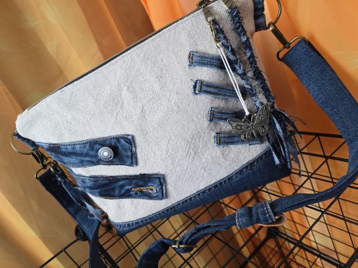 Tasche aus hellem Stoff mit dunkelblauen Denim-Elementen und Verzierungen.