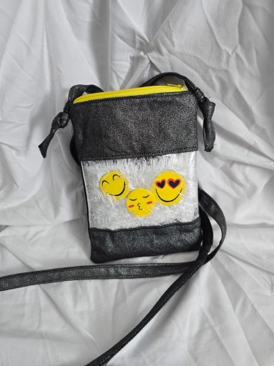 Schwarze Umhängetasche mit gelben Akzenten und Emoji-Aufklebern.