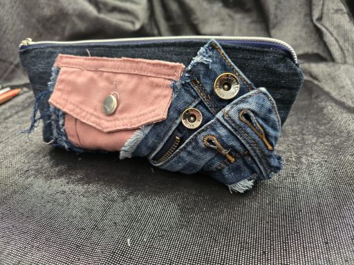 Bunte Federmappe aus recyceltem Jeansstoff mit verschiedenen Taschen und Knöpfen.
