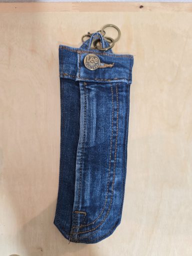 Jeans-tasche in dunklem Denim-Stil, mit Schlüsselring und abgerundeter Form.