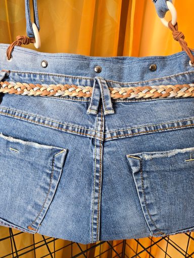 Jeans-Tasche aus blauem Denim mit geflochtenem Band und zwei hinteren Taschen.