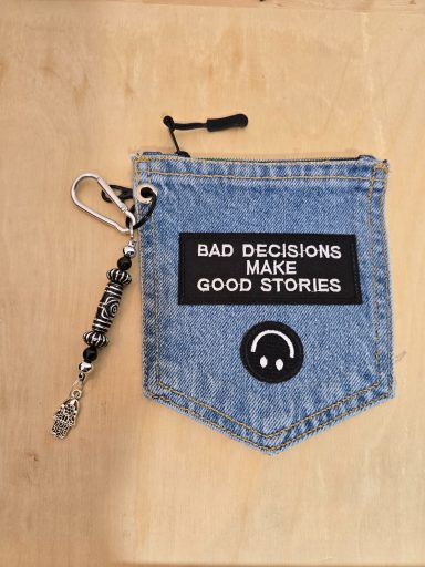 Denim-Tasche mit dem Aufdruck "Bad Decisions Make Good Stories" und Schlüsselanhänger.