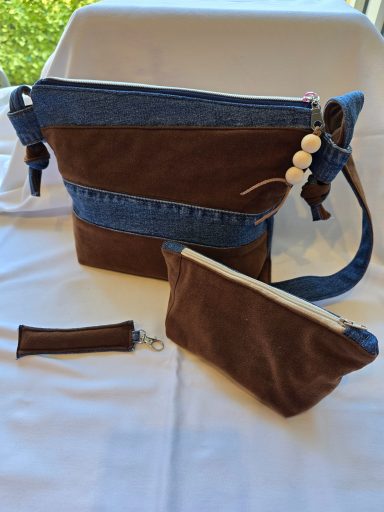 Drei Taschen in Braun und Blau mit Reißverschlüssen und dekorativen Knöpfen.