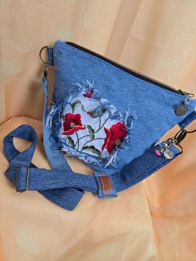 Blaues Umhängetasche mit floralem Design und Fransendetails.