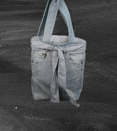 Helle Jeans-Tote mit Knoten und gepunktetem Innenfutter, auf dunklem Hintergrund.