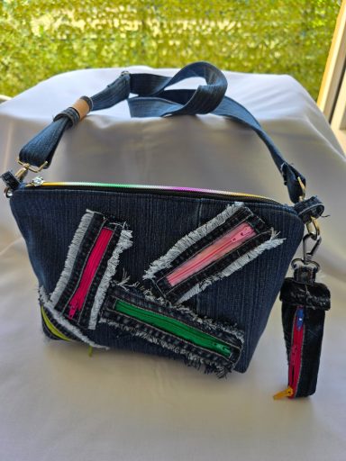 Tasche aus Jeansstoff mit bunten, fransigen Applikationen in verschiedenen Farben.