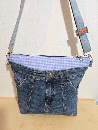 Tasche aus Jeansstoff mit kariertem Futter und verstellbarem Schultergurt.