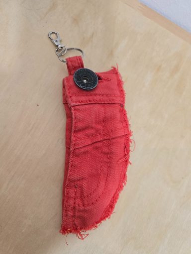 Rotes, fransiges Etui mit einem Knopf und Schlüsselanhänger.