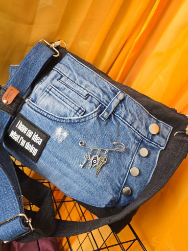 Tasche aus Denim mit aufgenähtem Patch und Knöpfen, farblich abgesetzt.