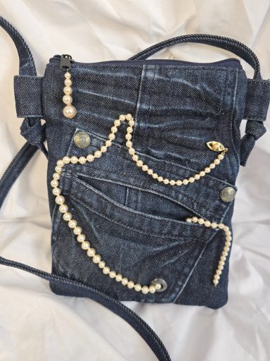 Tasche aus Jeansstoff mit Perlenverzierung und mehreren Taschen.