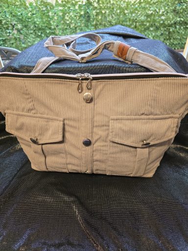 Beige Tasche mit zwei vorderen Taschen und Reißverschlussöffnung.