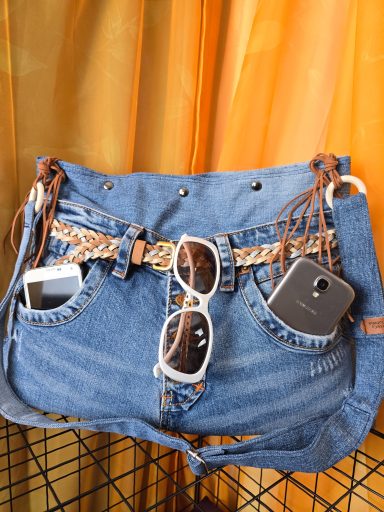 Jeans-Tasche mit Sonnenbrille, Smartphone und weiteren Accessoires.