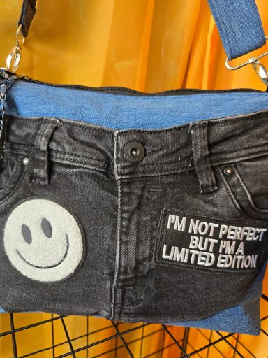 Schwarze Tasche aus Jeansstoff mit Smiley und Aufschrift "I'm not perfect but I'm a limited edition".