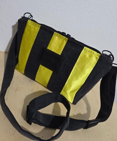 Schwarze Umhänge-Tasche mit gelbem H-Logo und länglichem Design.
