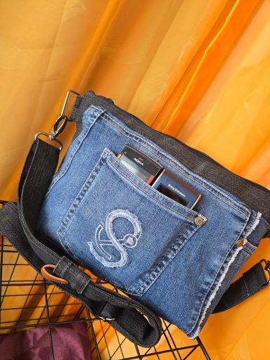 Helle Jeans-Tasche mit schwarzem Schultergurt und vorderer Tasche.