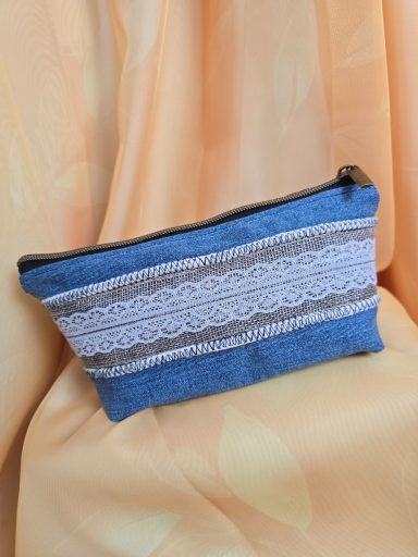 Dekorative Kosmetiktasche aus Jeansstoff mit einem weißen Spitzenmuster.