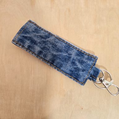 Schlüsselanhänger aus Jeansstoff in länglicher Form mit Schlüsselring.