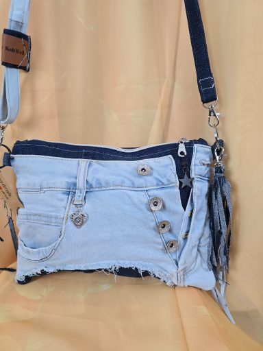 Tasche aus Denim mit fransigem Saum, Knopfdetails und Schultergurt.