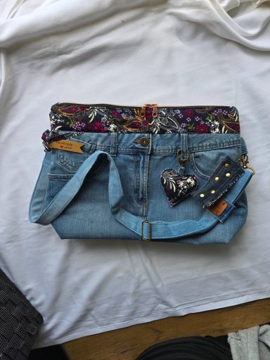 Jeans-Clutch mit buntem Stoff und abnehmbarem Anhänger auf einem weißen Hintergrund.