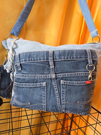 Tasche aus Jeansstoff mit zwei vorderen Taschen und verstellbarem Tragegurt.