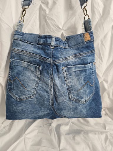 Handtasche aus Jeansstoff in der Form einer gefalteten Jeans mit Taschen.