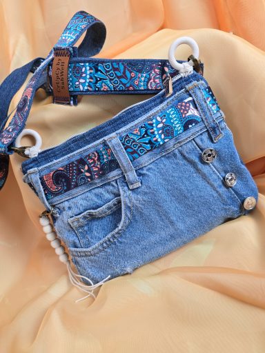 Tasche aus Jeansstoff mit buntem Riemen und dekorativen Knöpfen.