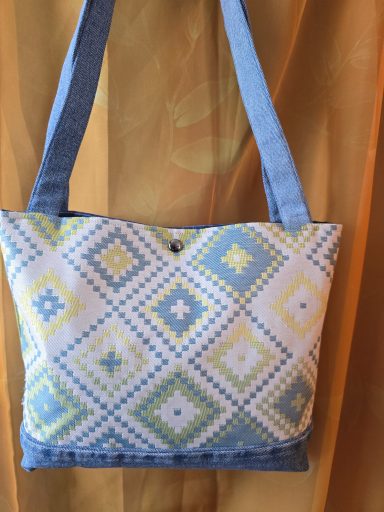 Bunte Handtasche mit geometrischem Muster in Blau, Gelb und Weiß.