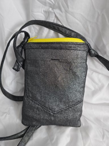 Schwarze Umhängetasche mit gelbem Reißverschluss und verstellbarem Trageriemen.