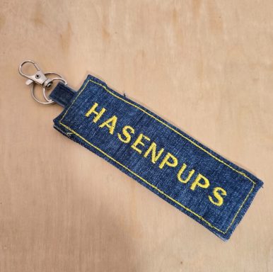 Schlüsselanhänger aus Jeansstoff mit gelbem Schriftzug "HASENPUPS".