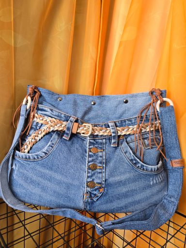 Denim Tasche mit Gürteldetail und braunen Lederriemen.